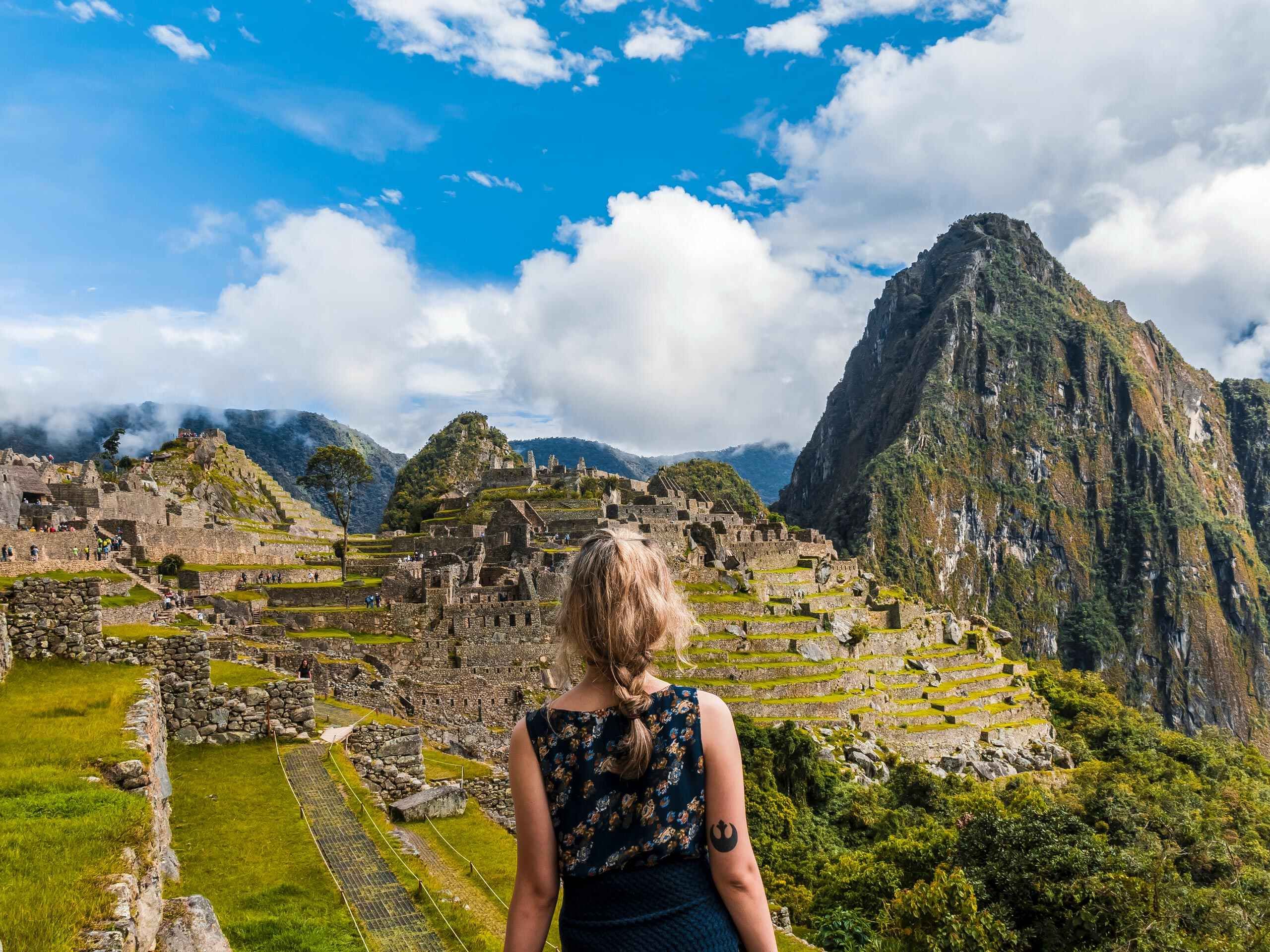 Hiker tourist stands facing ancient Machu Pichhu, Peru
